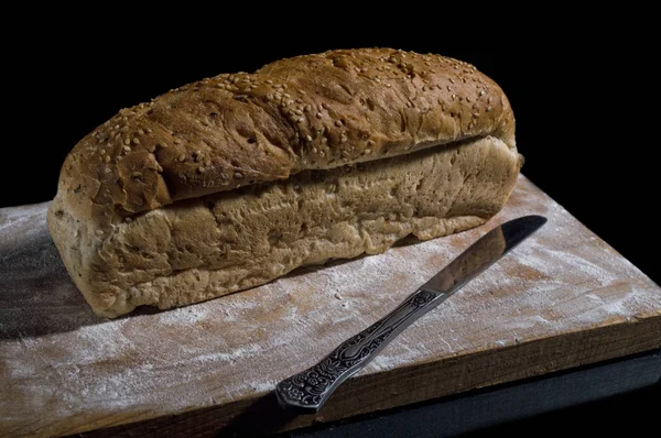Sliced bread and a knife on the kitchen board. Top view, black b — Stock Photo, Image