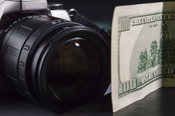 Крупный план объектива фотоаппарата и стодолларовая купюра Стоковая Картинка