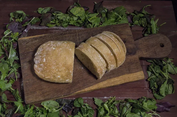 Sliced Ciabatta on a kitchen board with herbs — Stock Photo, Image