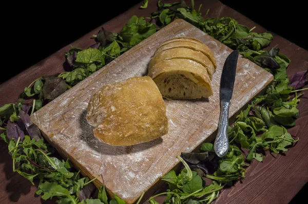 Italian ciabatta bread with knife on kitchen wooden board. Aroun — Stock Photo, Image