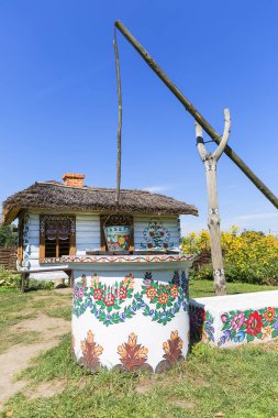 Zalipie, Polonya - 3 Ağustos 2018: eski ahşap evi, iyi ve kova bir el boyalı renkli çiçek motifleri, halk ile dekore edilmiş, boyalı