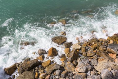 Taşlı plaj, turkuaz renkli su, dalgalar, beyaz köpük, Akdeniz, Cinque Terre, İtalya