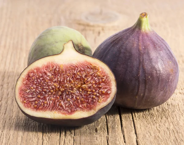 Fresh figs, half and whole on wooden plank, close up. Food photo — Stock Photo, Image