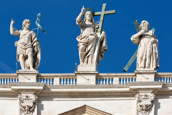 Ватикан, Рим, Италия - 9 октября 2020 года: Фигура Иисуса и апастолов на вершине фасада на голубом фоне неба