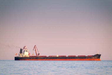 Gün batımında, sakin bir havada, büyük bir gemi denizde.