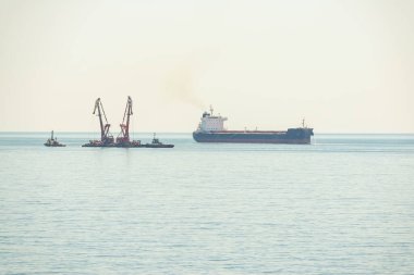 Limana yakın limanda yük gemisi ve yüzen vinçler var.