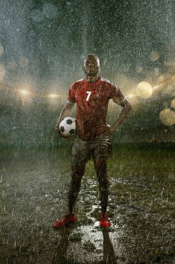 Profesyonel futbol gece yağmur stadyumda futbolcu. Futbol topu ile yağmur damlakirli oyuncu