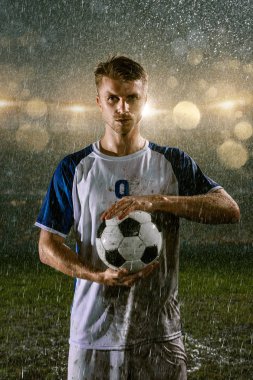 Profesyonel futbol gece yağmur stadyumda futbolcu. Futbol topu ile yağmur damlakirli oyuncu