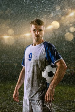 Profesyonel futbol gece yağmur stadyumda futbolcu. Futbol topu ile yağmur damlakirli oyuncu