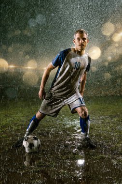 Profesyonel futbol gece yağmur stadyumda futbolcu. Futbol topu ile yağmur damlakirli oyuncu