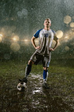 Profesyonel futbol gece yağmur stadyumda futbolcu. Futbol topu ile yağmur damlakirli oyuncu