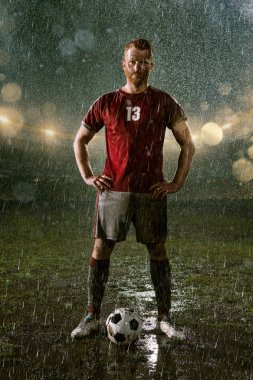 Profesyonel futbol gece yağmur stadyumda futbolcu. Futbol topu ile yağmur damlakirli oyuncu