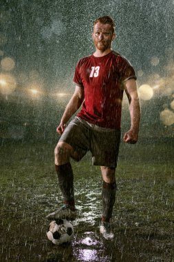 Profesyonel futbol gece yağmur stadyumda futbolcu. Futbol topu ile yağmur damlakirli oyuncu