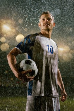Profesyonel futbol gece yağmur stadyumda futbolcu. Futbol topu ile yağmur damlakirli oyuncu