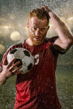 Profesyonel futbol gece yağmur stadyumda futbolcu. Futbol topu ile yağmur damlakirli oyuncu