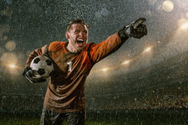 Profesyonel futbol gece yağmur stadyumda Futbol kalecisi. Futbol topu ile yağmur damlakirli oyuncu