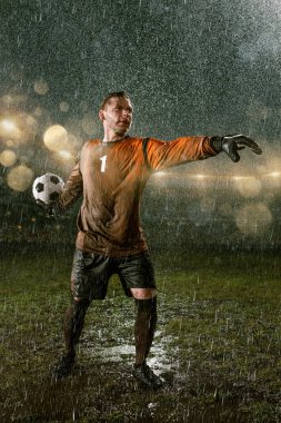 Profesyonel futbol gece yağmur stadyumda Futbol kalecisi. Futbol topu ile yağmur damlakirli oyuncu