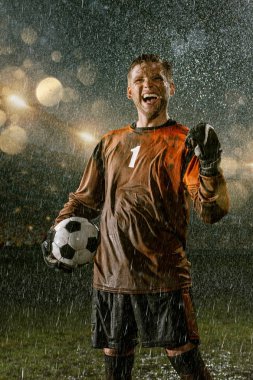 Profesyonel futbol gece yağmur stadyumda Futbol kalecisi. Futbol topu ile yağmur damlakirli oyuncu