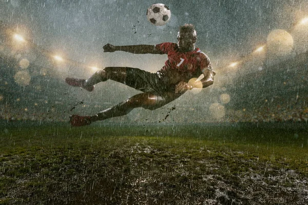 サッカー選手は プロの夜の雨のスタジアムでアクションプレイを行います 雨の中の汚れた選手はゴールを決める 雨で濡れたスタジアムの草 — ストック写真