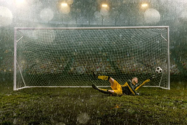 飛行中の汚れたゴールキーパーがボールをキャッチします サッカーの目標を持つプロの夜の雨のスタジアム 雨で濡れたスタジアムの草 — ストック写真