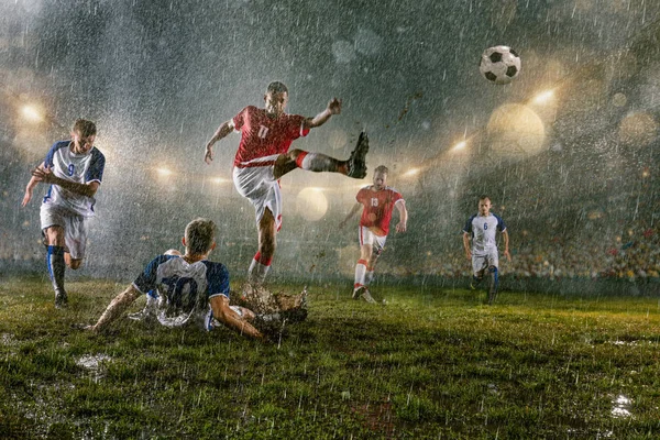 サッカー選手は プロの夜の雨のスタジアムでアクションプレイを行います 雨の中の汚れた選手はゴールを決める 雨で濡れたスタジアムの草 — ストック写真