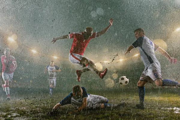 足球运动员在专业的夜雨体育场表演动作剧 肮脏的球员在雨中丢球得分 体育场上的草被雨淋湿了 — 图库照片