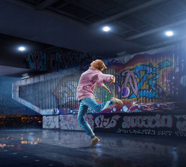 Female Hip Hop Dancer. Beautiful girl dancing at night on the background of graffiti wall