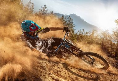 Orman yolunda dağ bisikletçisi. Erkek bisikletçi kayaya biniyor