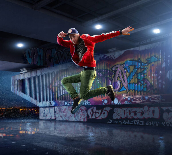 Male Hip Hop Dancer. Beautiful man dancing at night on the background of graffiti wall