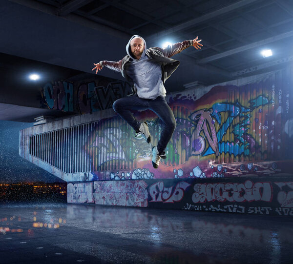 Male Hip Hop Dancer. Beautiful man dancing at night on the background of graffiti wall