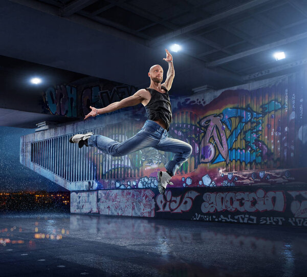 Male Hip Hop Dancer. Beautiful man dancing at night on the background of graffiti wall