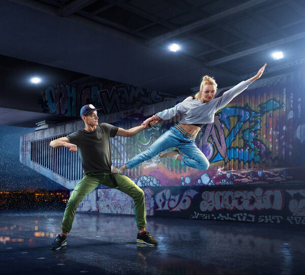Hip Hop Dancers. Beautiful couple dancing at night on the background of graffiti wall