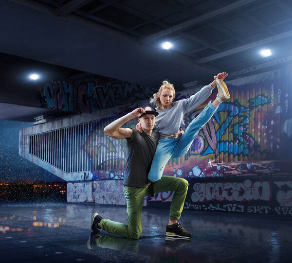 Hip Hop Dancers. Beautiful couple dancing at night on the background of graffiti wall