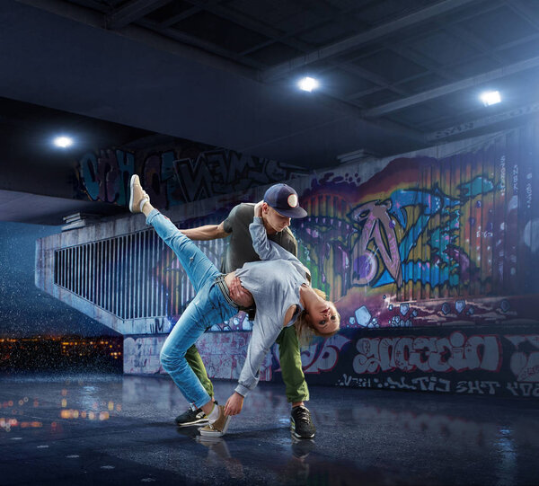 Hip Hop Dancers. Beautiful couple dancing at night on the background of graffiti wall