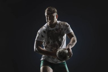 Karanlık arka planda rugby topu ile izole kirli rugby oyuncusu