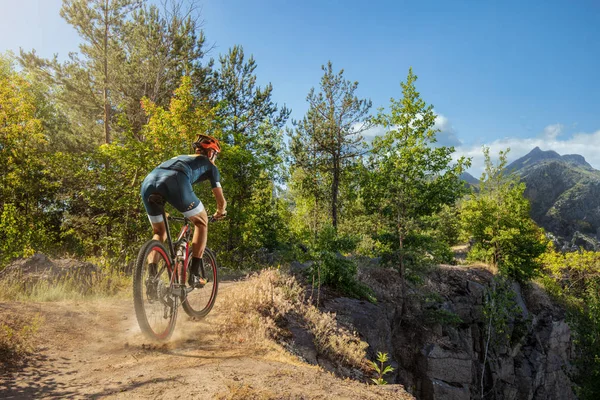 Cross-Country biker on trail. Male cyclist rides the rock