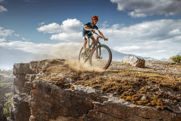 Cross-Country biker on trail. Male cyclist rides the rock