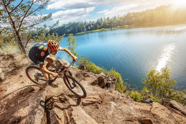 Cross-Country biker on trail. Male cyclist rides the rock