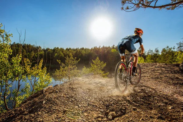 Cross-Country biker on trail. Male cyclist rides the rock