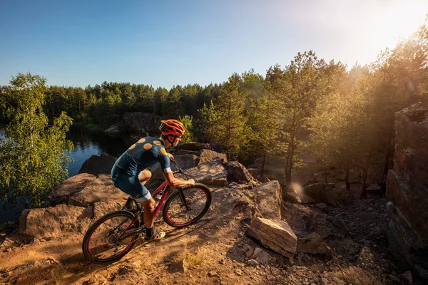 Cross-Country biker on trail. Male cyclist rides the rock