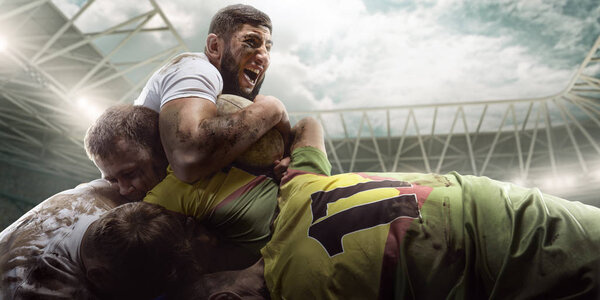 Rugby players fight for the ball on professional rugby stadium