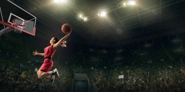Kadın basketbolcu smaç yapıyor. Basketbolcu oyun sırasında büyük profesyonel arenada