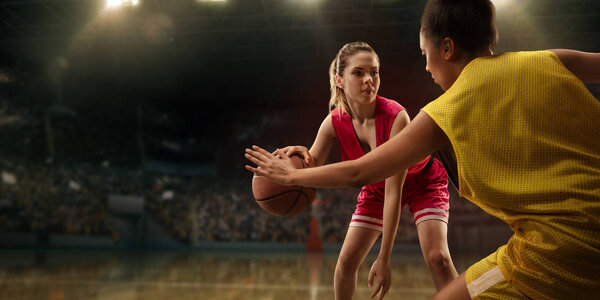 Female basketball players fight for the ball. Basketball players on big professional arena during the game