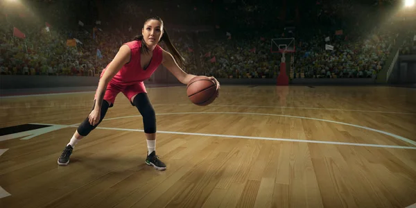 Female basketball player with ball on big professional arena