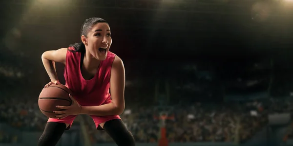 Female basketball player with ball on big professional arena