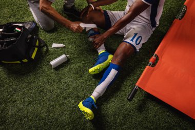 Futbol oyuncusu diz yaralandı oyun sırasında. Spor doktorlar profesyonel bir futbol alanında oyuncuya ilk yardım sağlar. Yakın çekim
