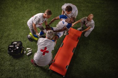 Futbol oyuncusu oyun sırasında bacak yaralandı. Spor doktorlar profesyonel bir futbol alanında oyuncuya ilk yardım sağlar