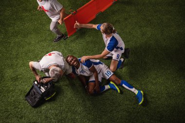 Futbol oyuncusu oyun sırasında bacak yaralandı. Spor doktorlar profesyonel bir futbol alanında oyuncuya ilk yardım sağlar
