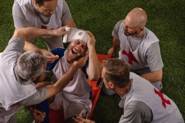 Futbol oyuncusu oyun sırasında baş yaralanması aldı. Spor doktorlar profesyonel bir futbol alanında oyuncuya ilk yardım sağlar