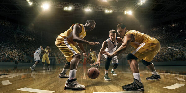 Basketball players on big professional arena during the game. Male basketball players fight for the ball